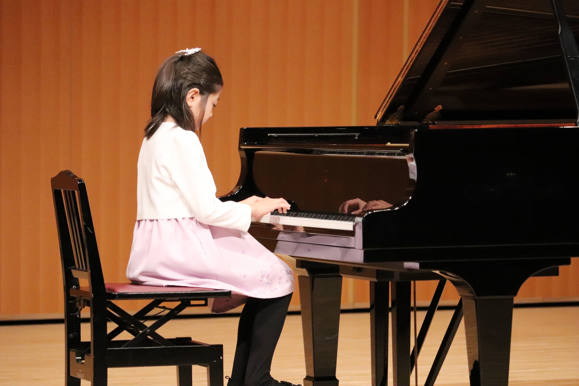 ホールでグランドピアノを演奏する子ども